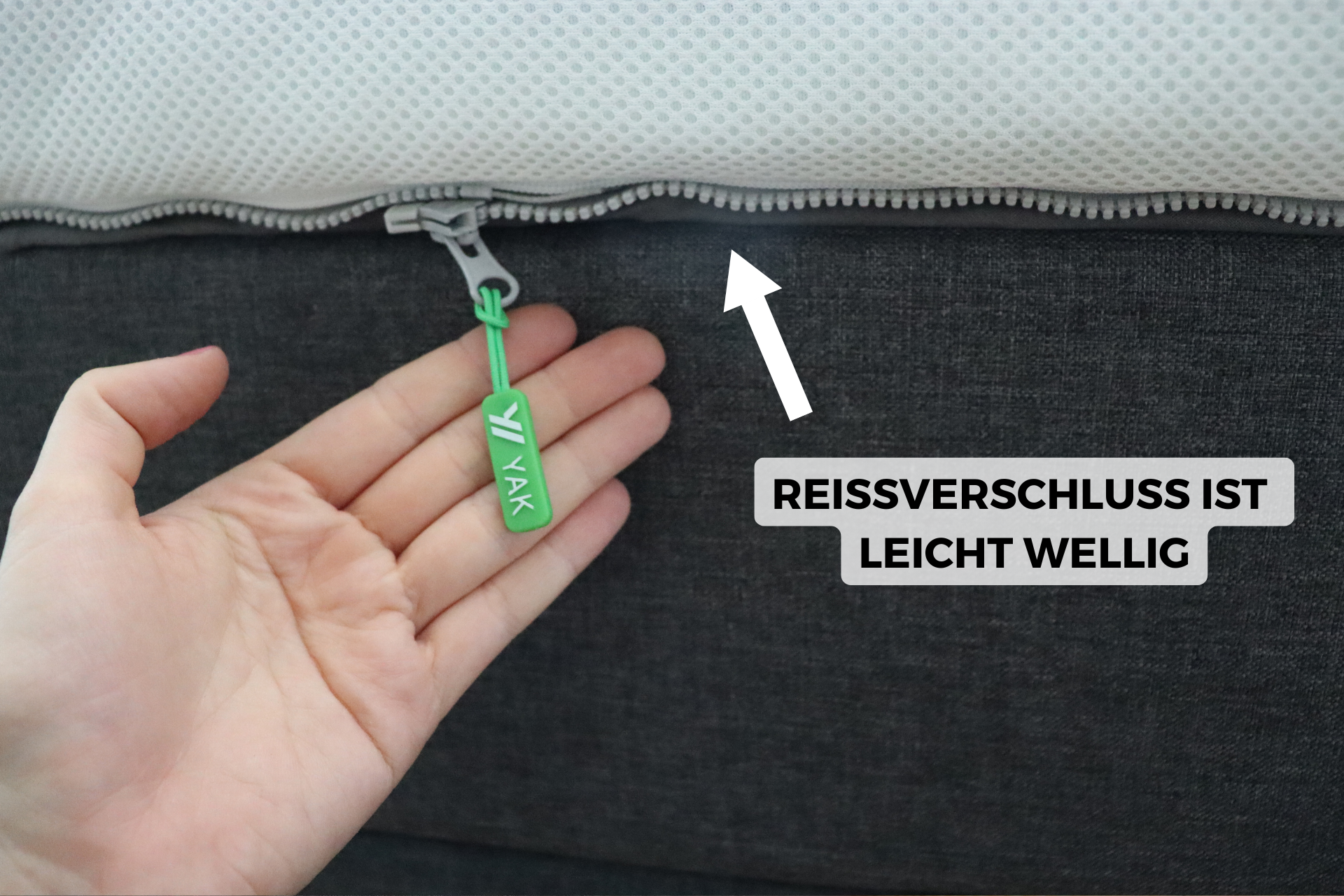Eine Person hält den Reißverschluss des Toppers in der Hand.